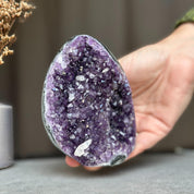 Hand holding a vibrant deep purple Uruguayan amethyst geode cluster, 3x4 inches, with sparkling crystals.