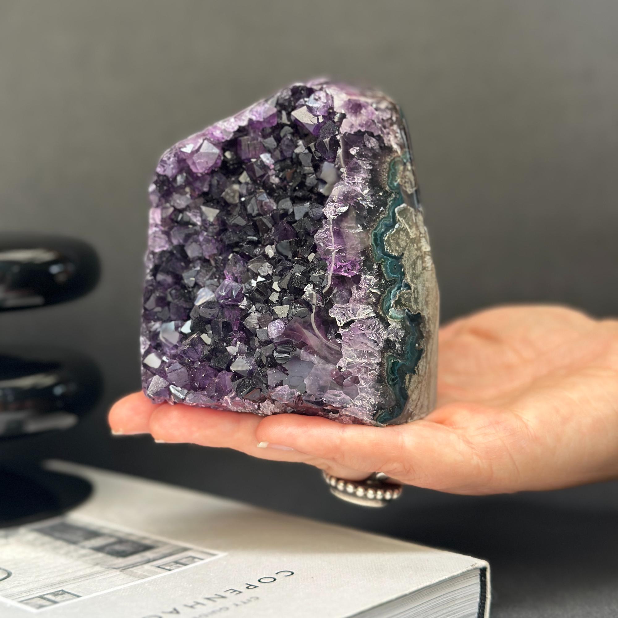 Deep purple amethyst cathedral geode with green agate formation, held in a hand.