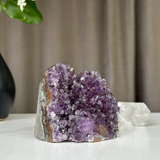 Deep purple Uruguayan amethyst geode cluster, 3x3 inch, 1.2 lb, on a white surface.