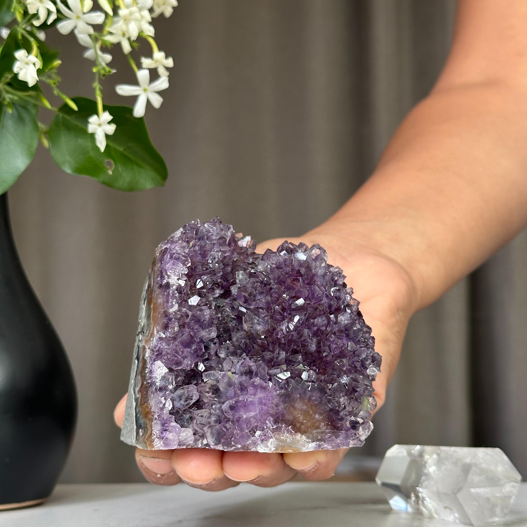 Hand holding a vibrant deep purple Uruguayan amethyst crystal cluster, 3x3 inches.