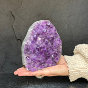 Hand holding a deep purple amethyst cathedral geode, 6-inch tall, with sparkling crystal points.