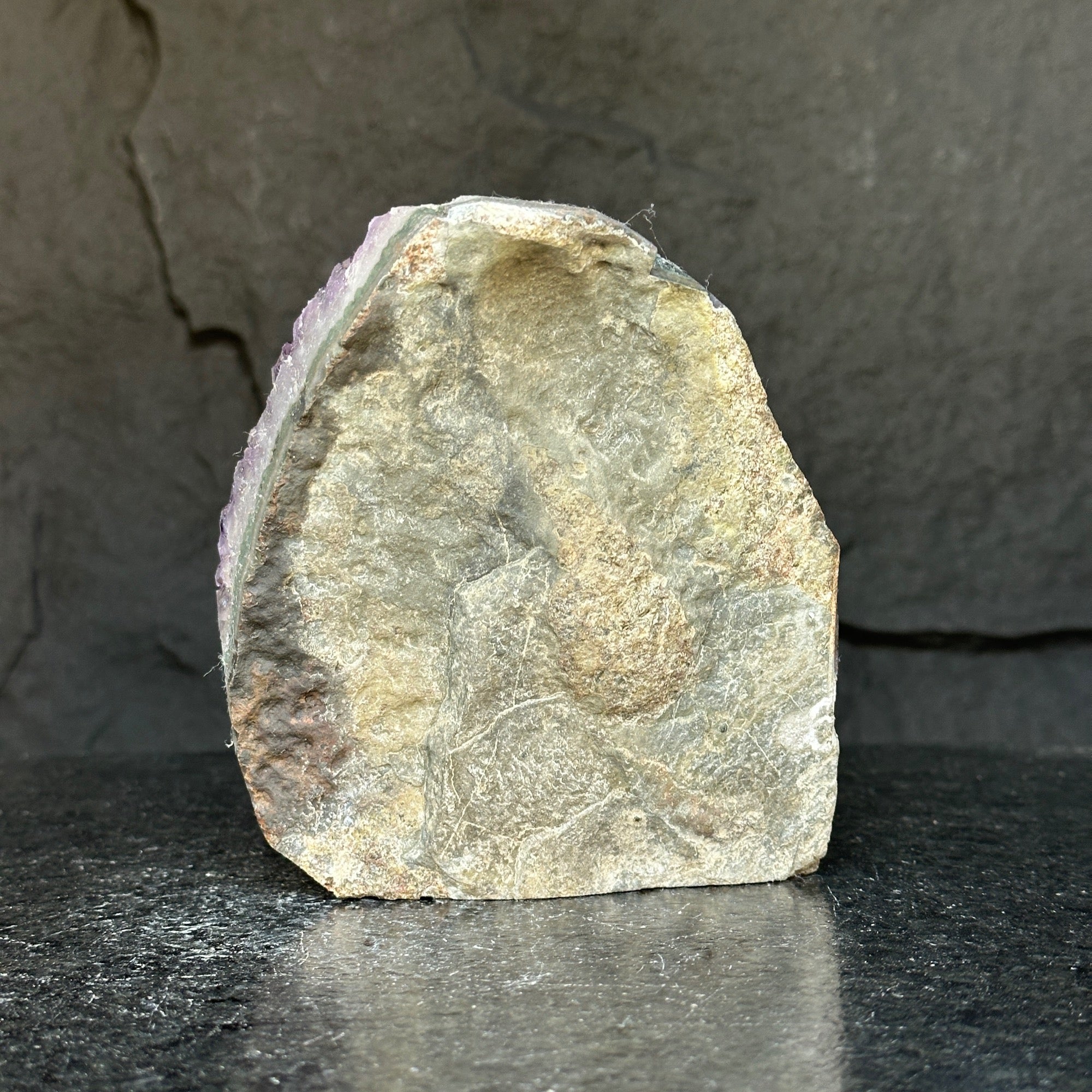 Rough back of a deep purple amethyst cathedral geode, showing natural stone texture.