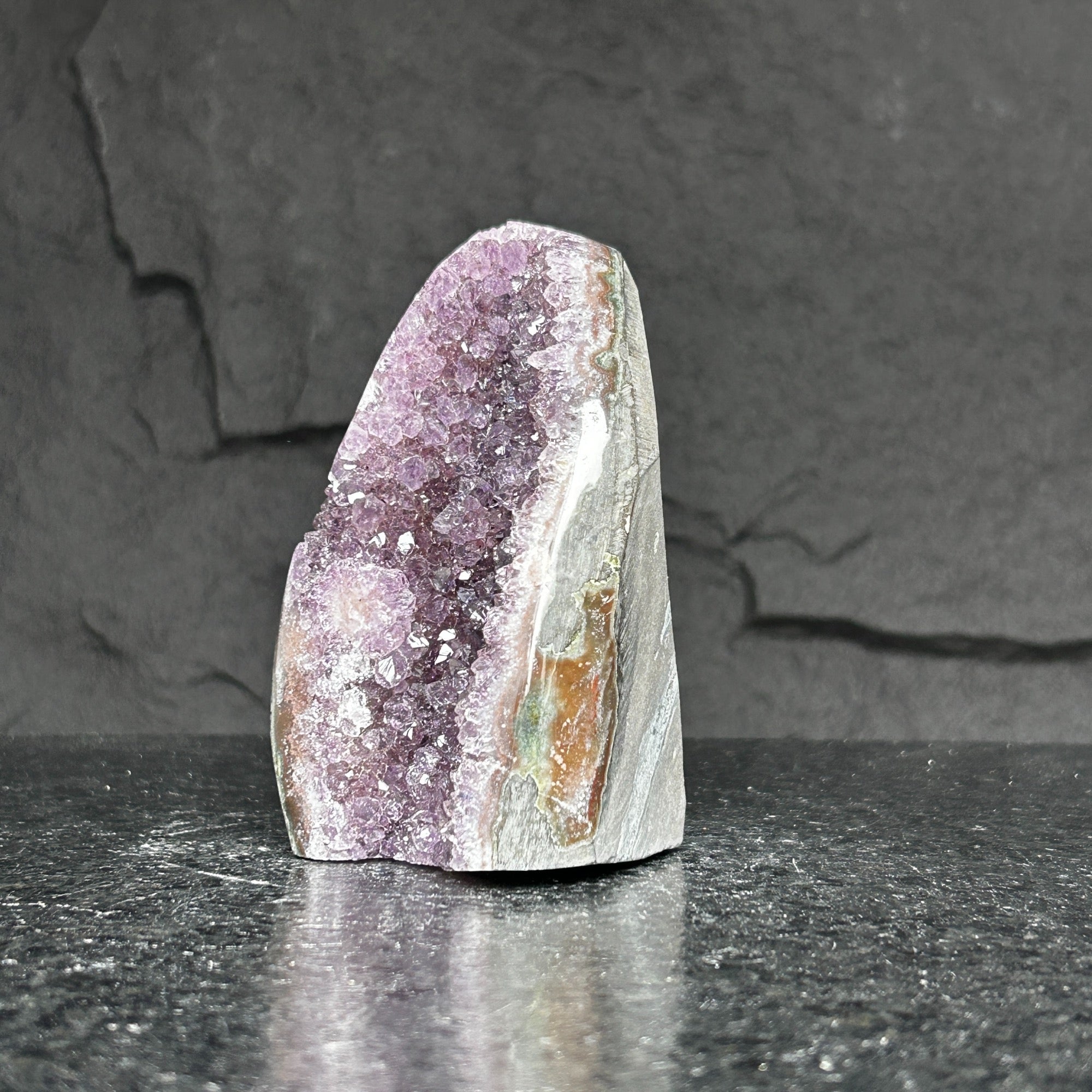 Extra large amethyst cluster, standing, with vibrant purple crystals inside natural grey and brown rock.