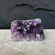 Flat, vibrant deep purple raw amethyst crystal cluster, 0.9 lb, on a light surface.