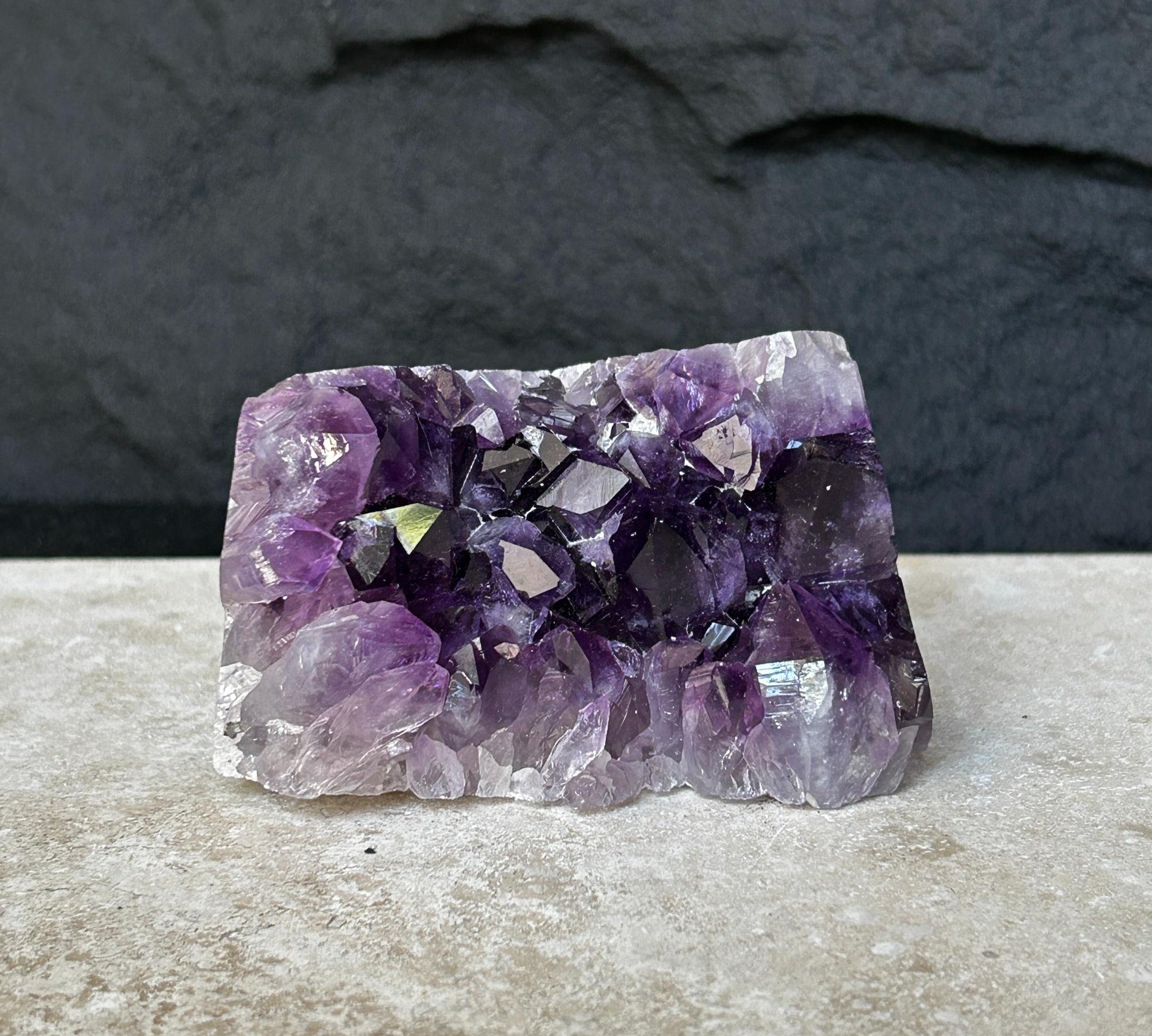 Flat, vibrant deep purple raw amethyst crystal cluster, 0.9 lb, on a light surface.