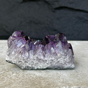 Flat, raw amethyst crystal cluster with vibrant deep purple points and a natural grey base.