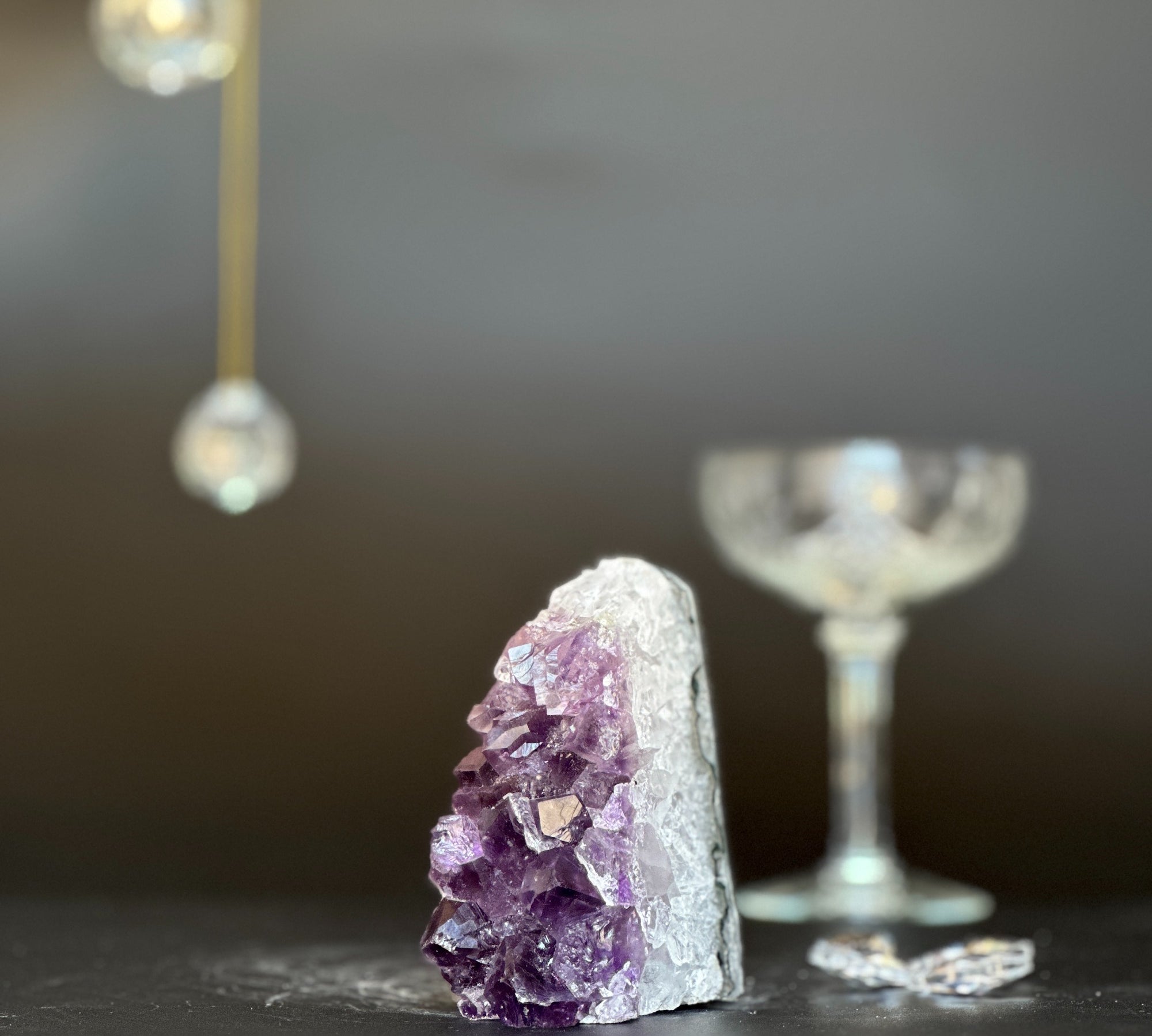 Vibrant purple amethyst geode with white crystal base, 3.5 inches tall, next to a blurred glass.