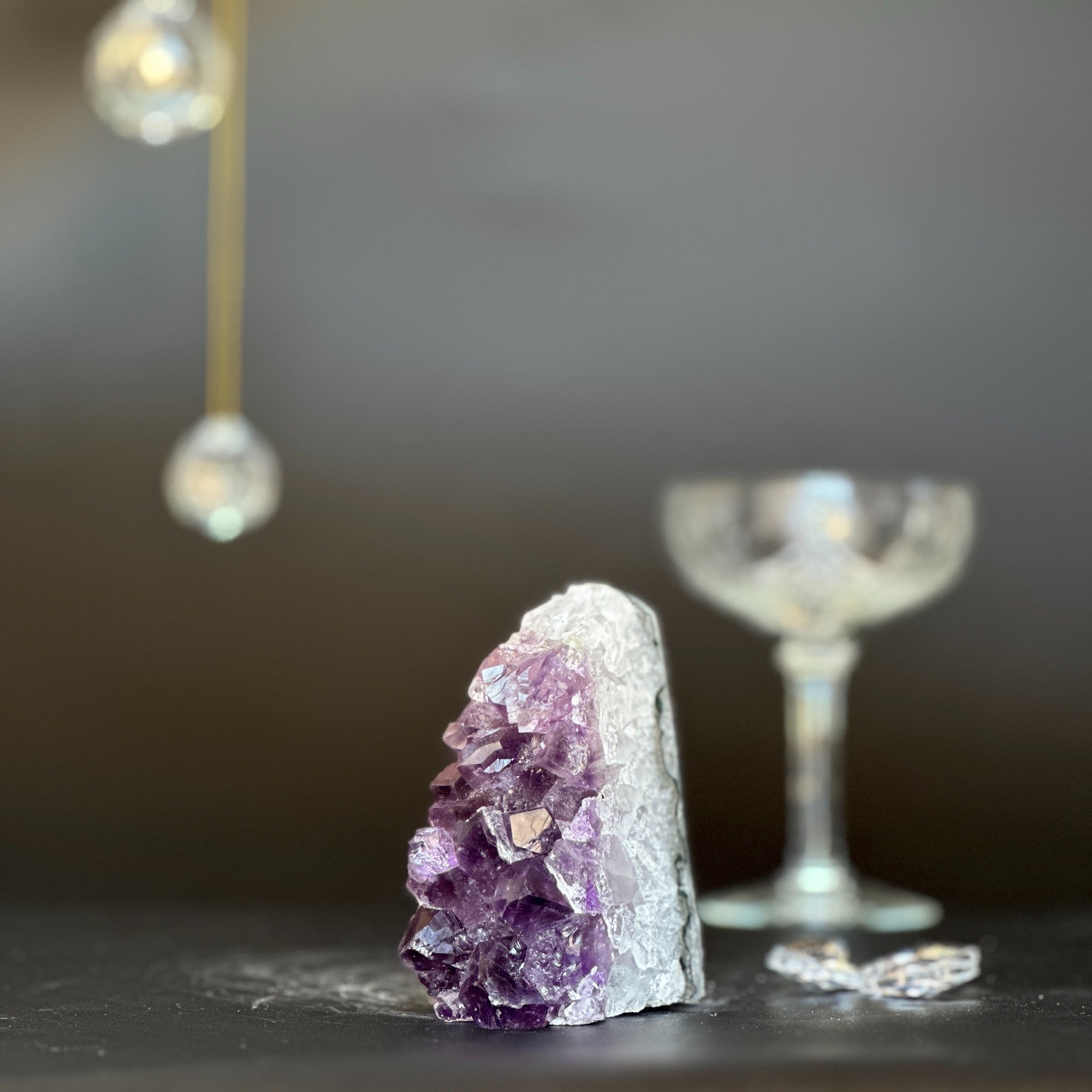 Vibrant purple amethyst geode with white crystal base, 3.5 inches tall, next to a blurred glass.