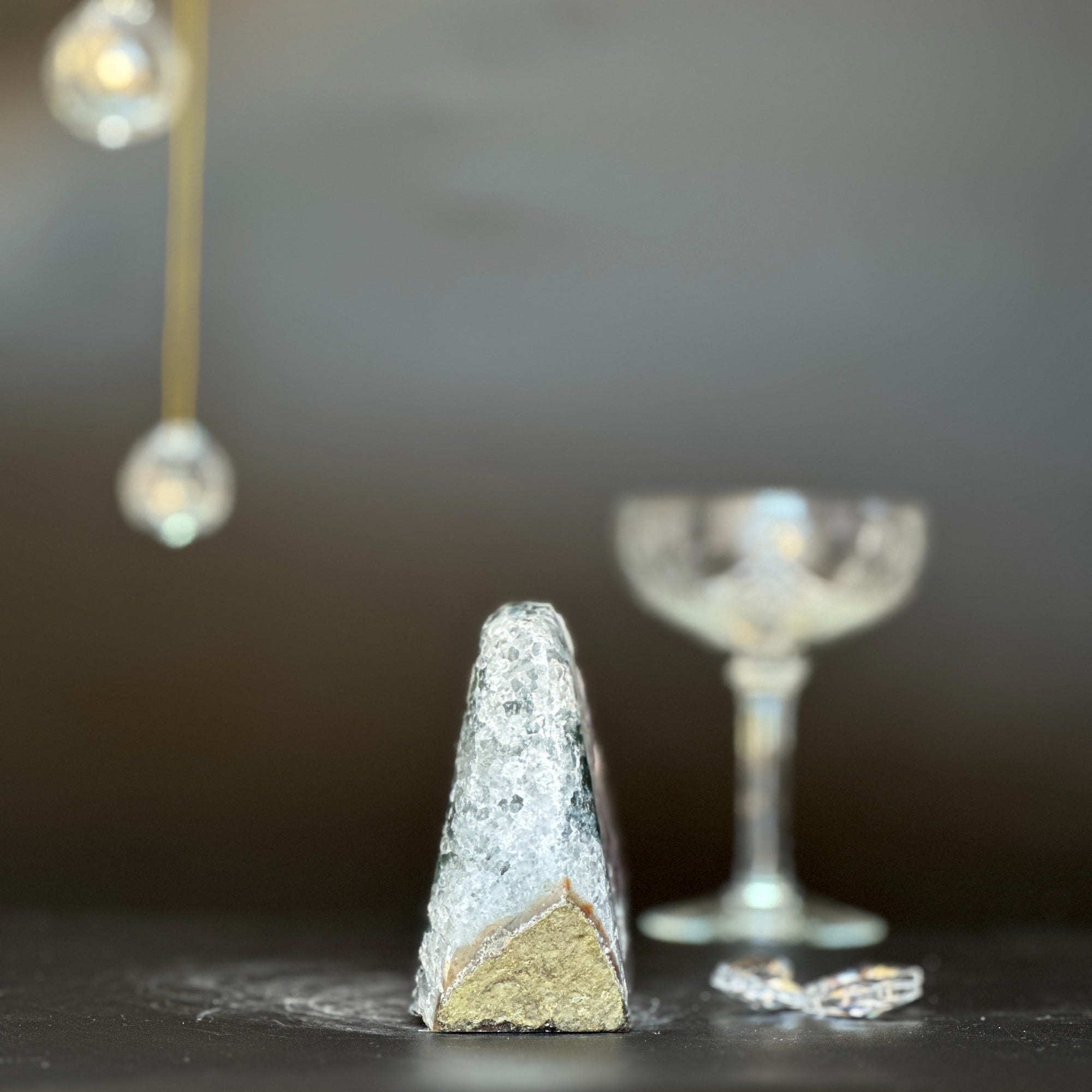 Sparkling Galaxy Amethyst geode, 3.5 inches tall, with a rough gold base, next to a crystal glass.