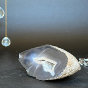 Polished agate geode with a white crystal cave and gray bands on a dark background.