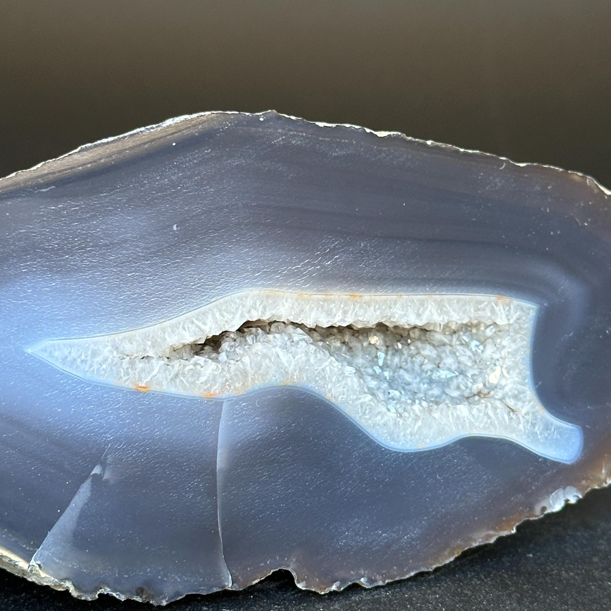 Polished blue-gray agate slice with a white crystal geode cavity.