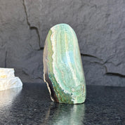 Green Jasper Flame gemstone, 5.5-inch tall, with natural striped patterns on a dark background.