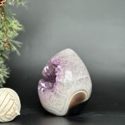 Polished deep purple amethyst geode egg with crystal points and brown agate formations.