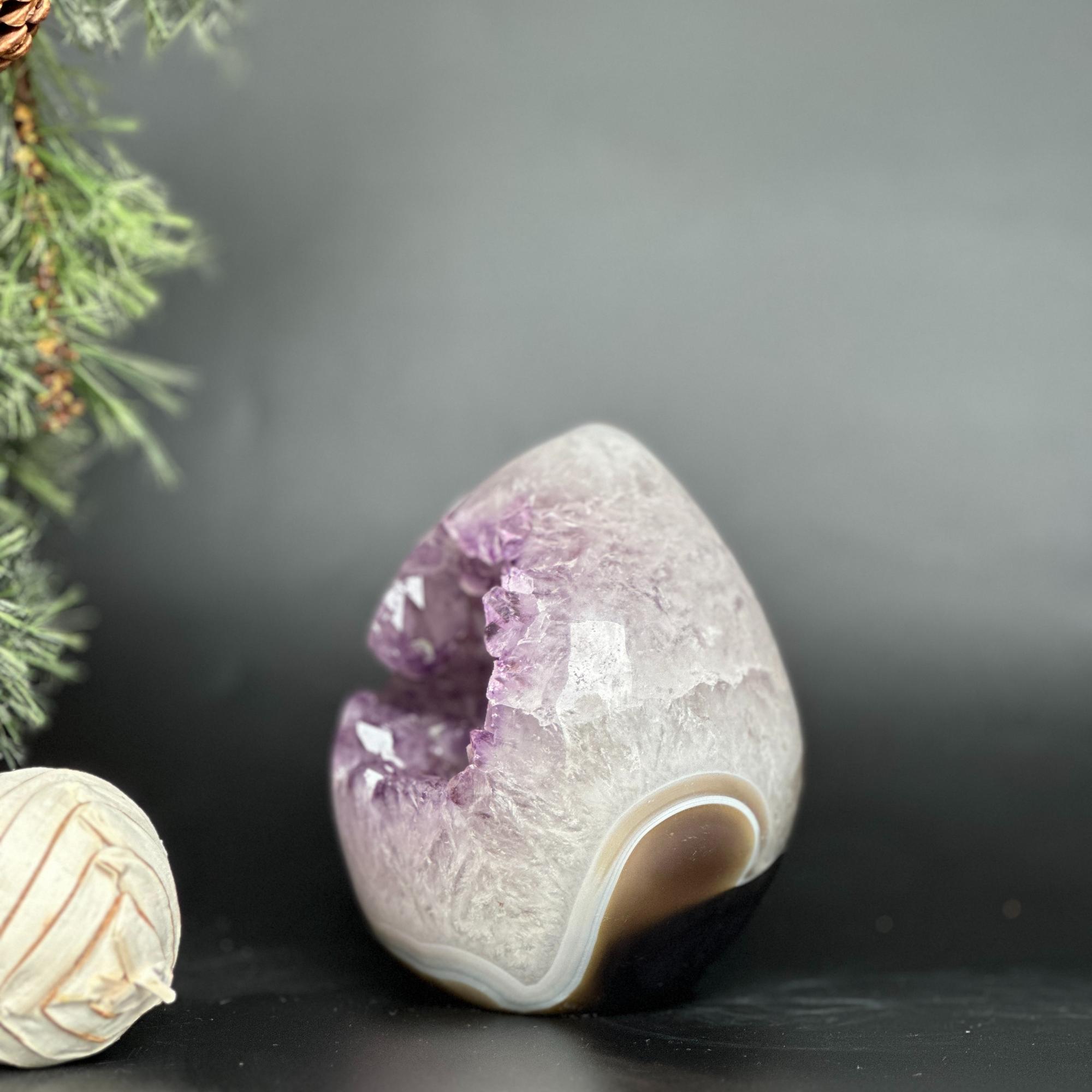 Polished deep purple amethyst geode egg with crystal points and brown agate formations.