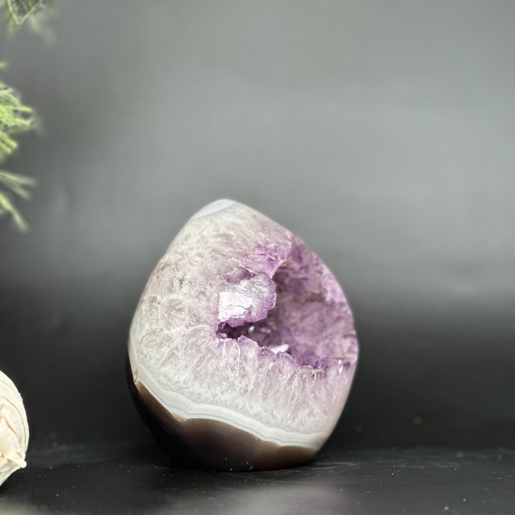 Deep purple amethyst geode egg, polished oval crystal with natural agate bands and sparkling points.