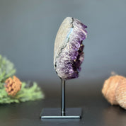 Large, deep purple Uruguayan amethyst geode crystal on a black metal stand.