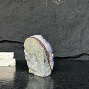 Large Uruguayan amethyst geode with deep purple crystals and a natural grey and reddish-brown rock exterior.