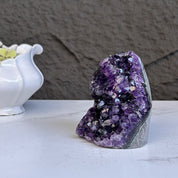 Large deep purple amethyst geode crystal cluster with sparkling formations.