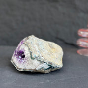 Raw crystal rock with purple interior on a dark surface