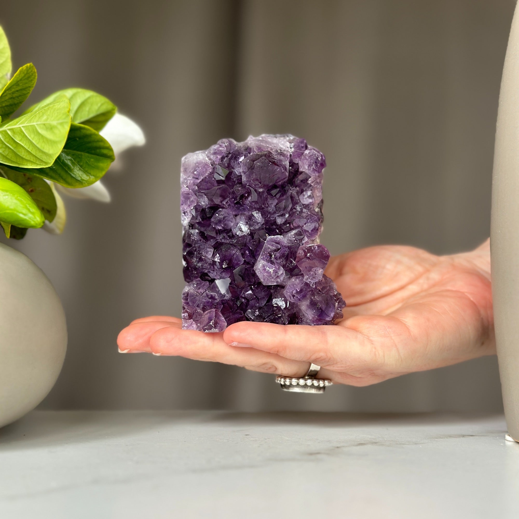 Hand holding a vibrant purple amethyst geode with large crystals, 3.5 inches tall.