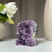 Vibrant purple amethyst geode, 3.5-inch tall, 1.1 lb, with sparkling crystals on a white surface.