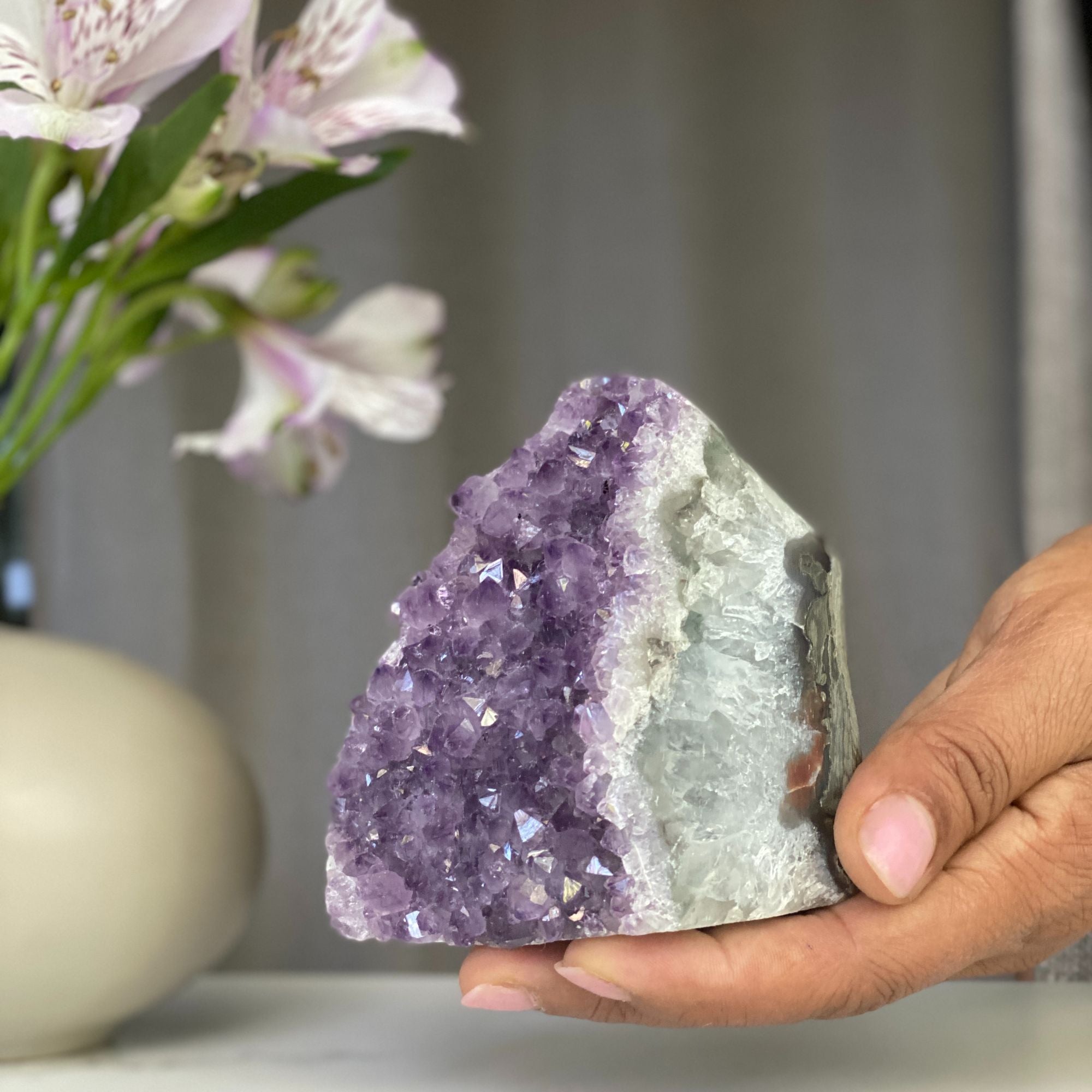 Vibrant lavender amethyst geode cluster with sparkling purple crystals and white agate formations.