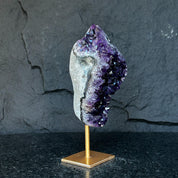 Natural Uruguayan amethyst cave crystal with deep purple geode on a gold metal stand.