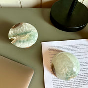 Round glass object on a book with a laptop and bowl in the background.