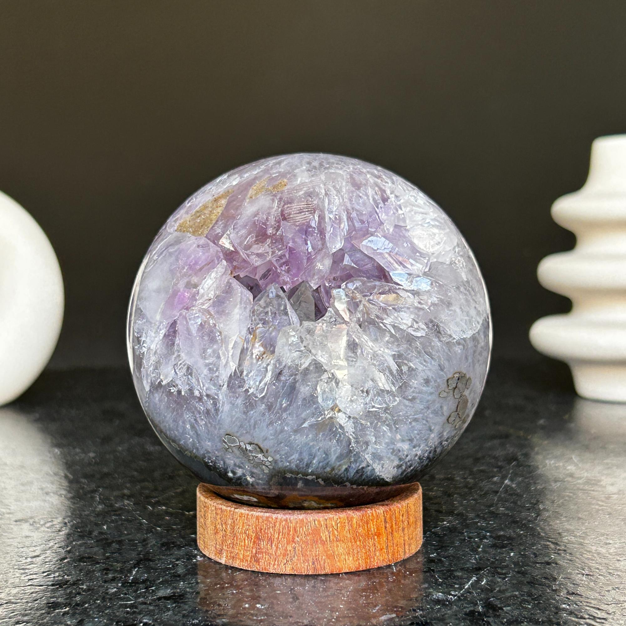 Polished deep violet amethyst sphere with white and black agate on a carob wood base.