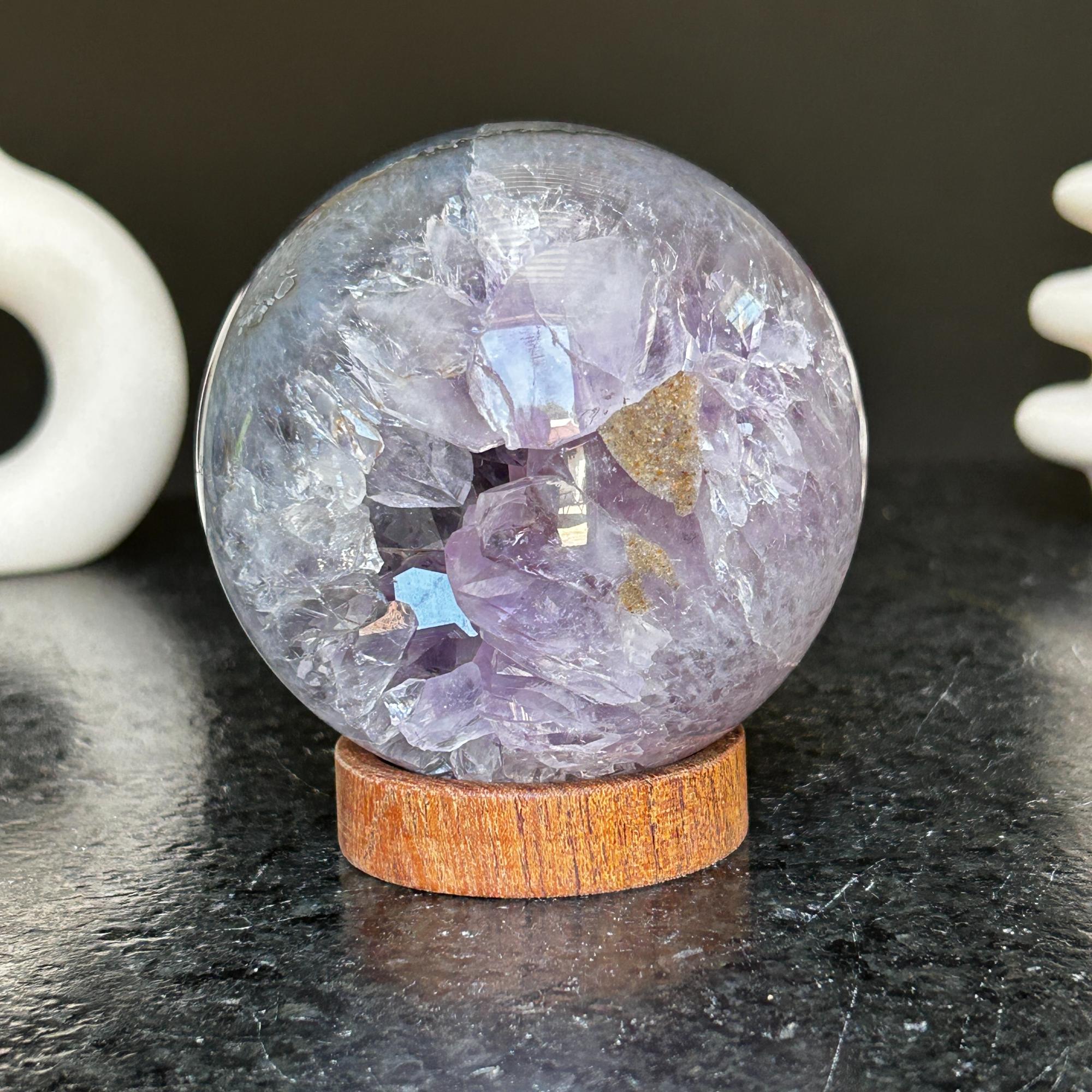 Polished deep violet amethyst sphere with white and black agate on a carob wood base.