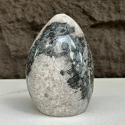 Polished 5-inch quartz, amethyst, and agate stone egg with black, white, and gray patterns.