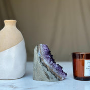 Deep purple Uruguayan amethyst geode cluster, 3.5-inch tall, with a white vase and amber candle.