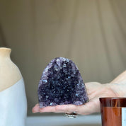 Deep purple raw amethyst crystal geode cluster held in a hand, showcasing its vibrant color.