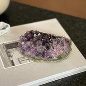 Deep purple raw flat amethyst cluster from Uruguay, 0.9lb, on a white book.