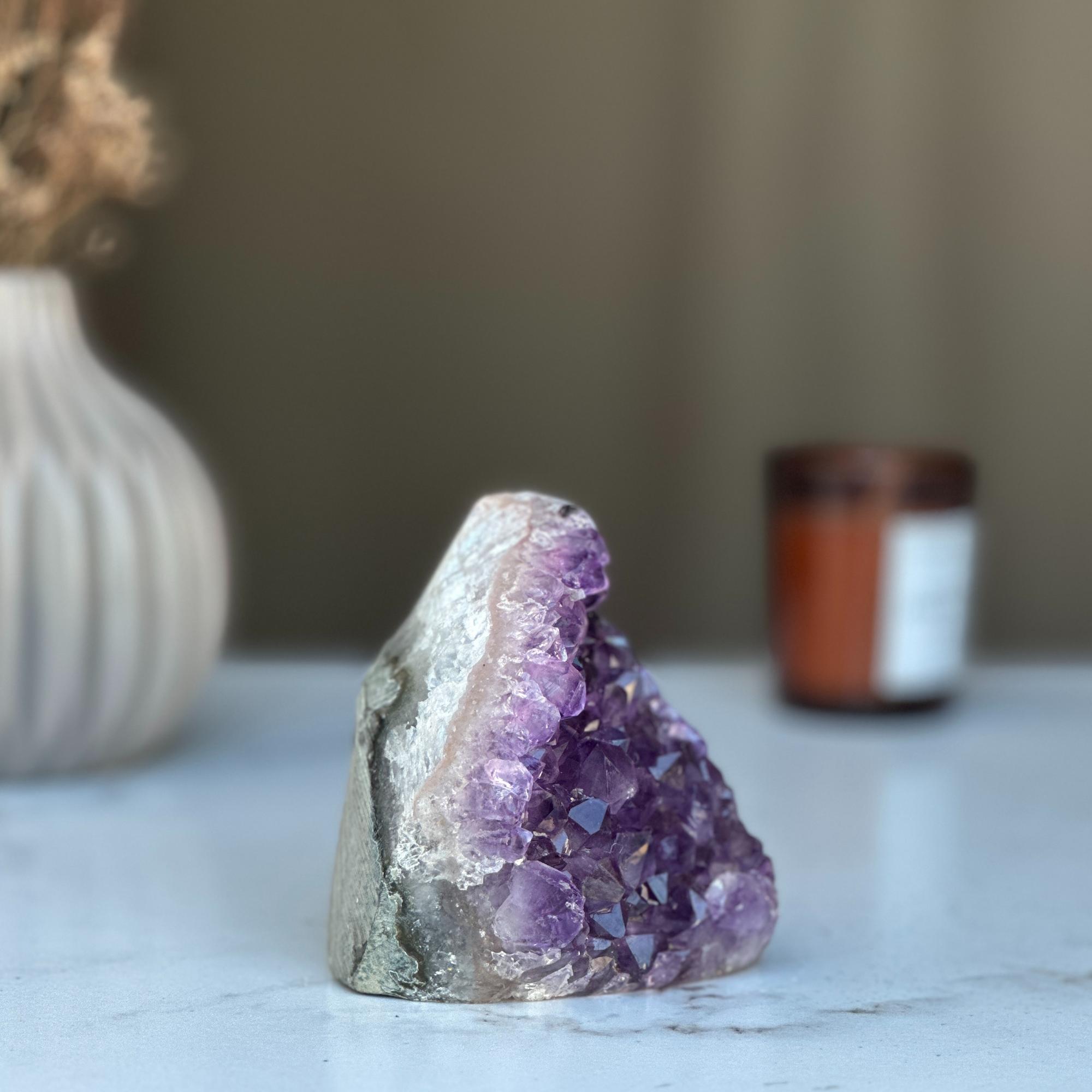 Raw purple amethyst geode crystal cluster, 3.5 in tall, on a white marble surface.