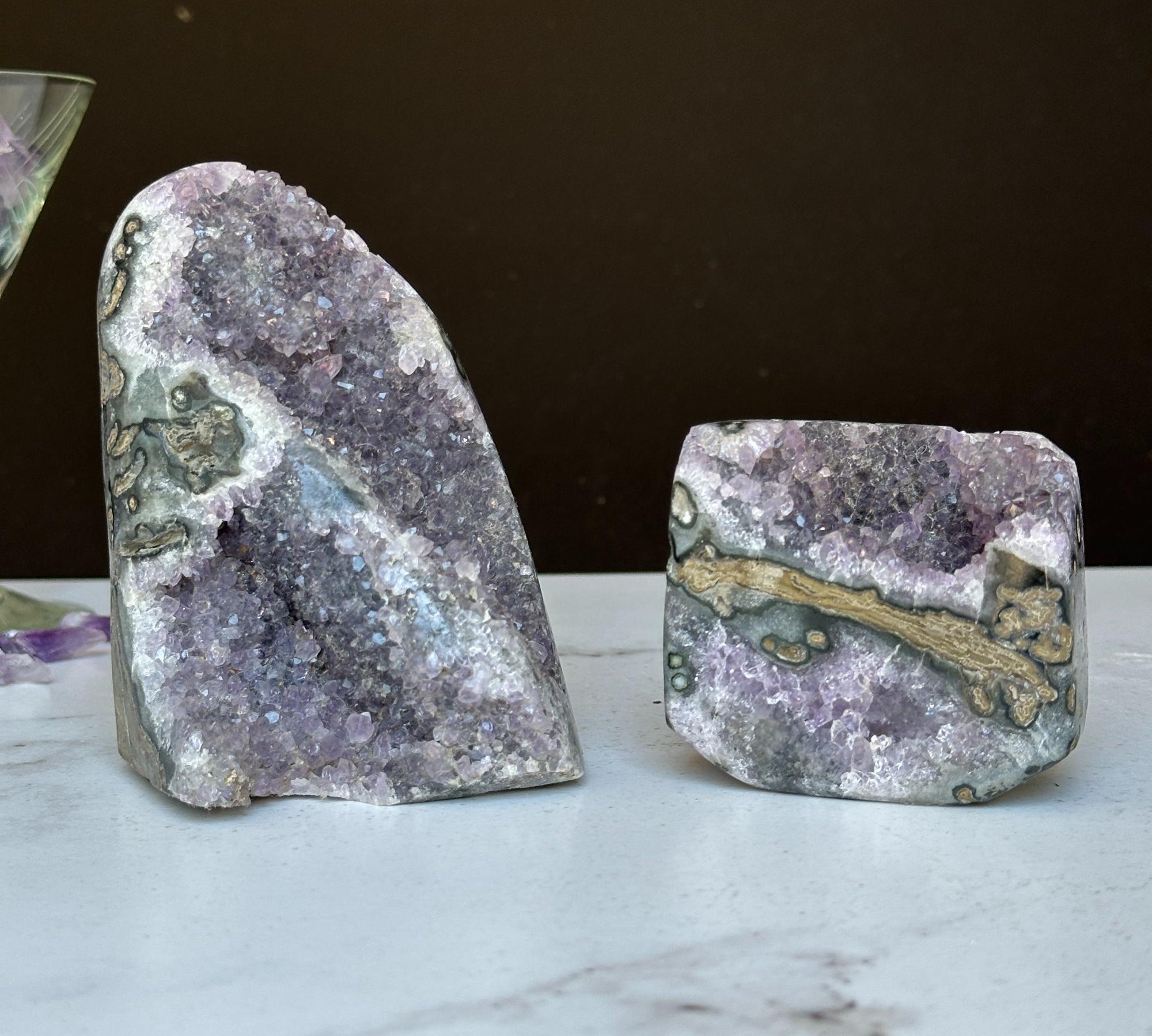 Two vibrant Uruguayan amethyst geode clusters with agate formations, one tall and one shorter.