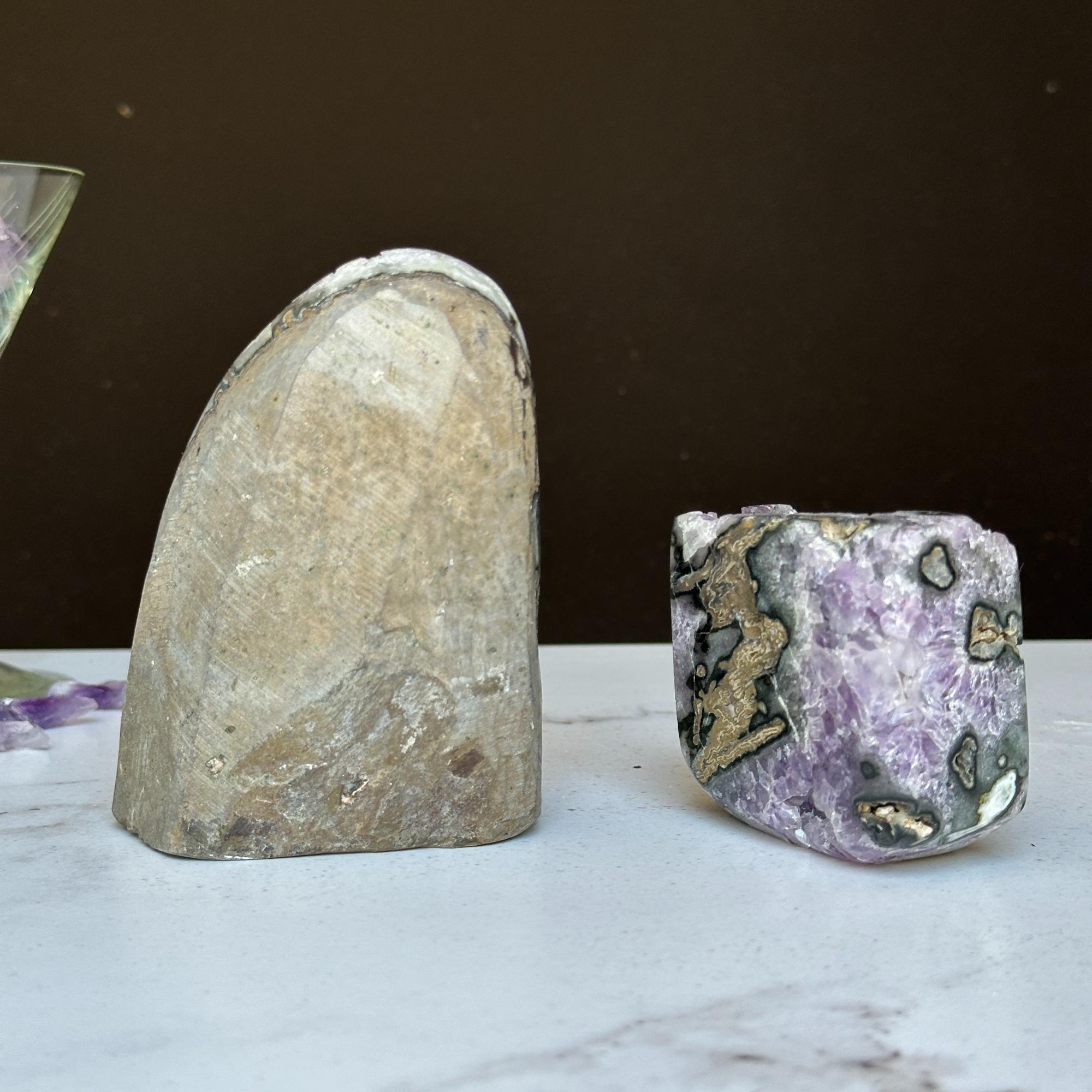 Two Uruguayan amethyst clusters with agate, one tall gray geode and one vibrant purple cube.