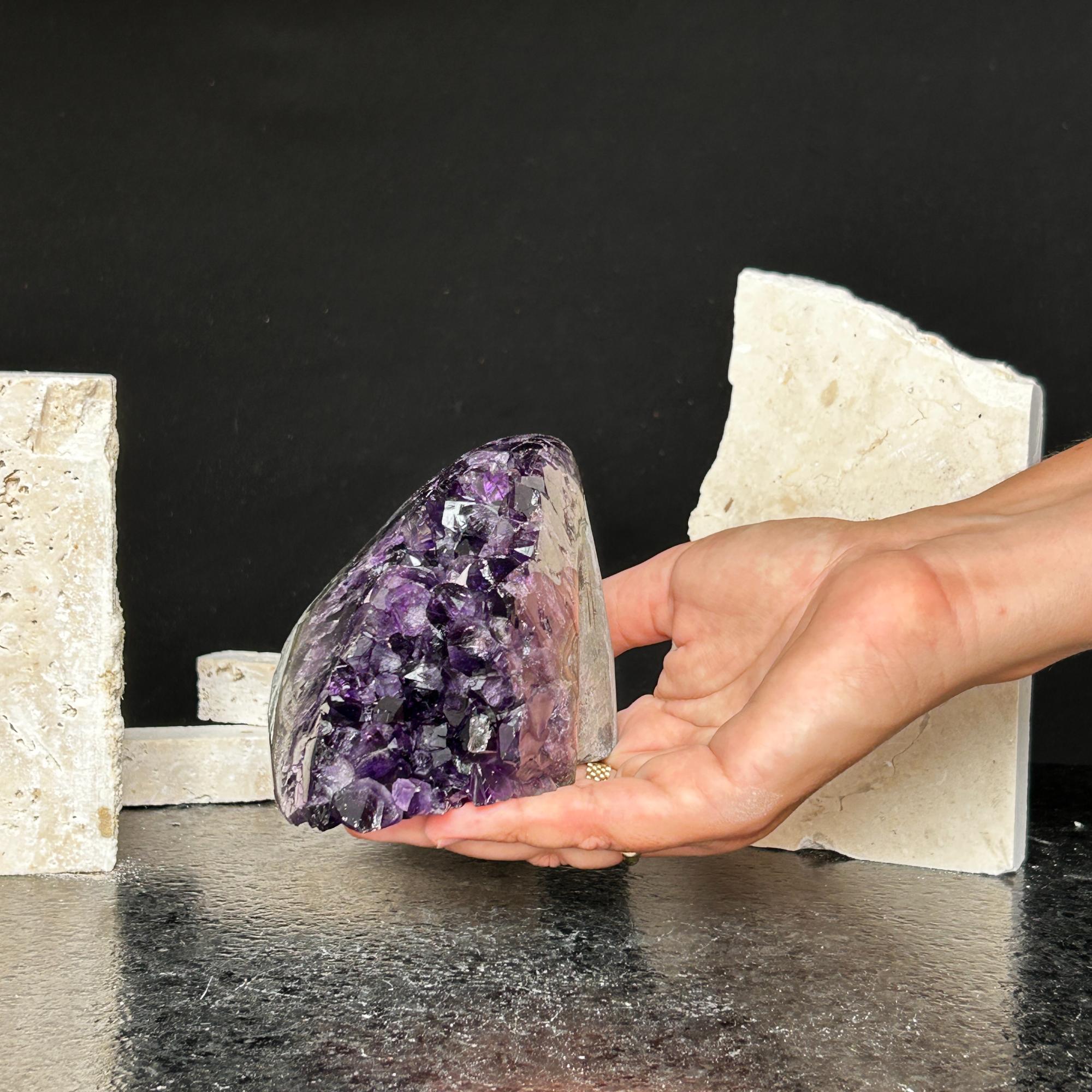 Hand holding a deep purple Uruguayan amethyst cluster with agate formations.