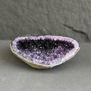 Amethyst geode on a gray surface with a dark background