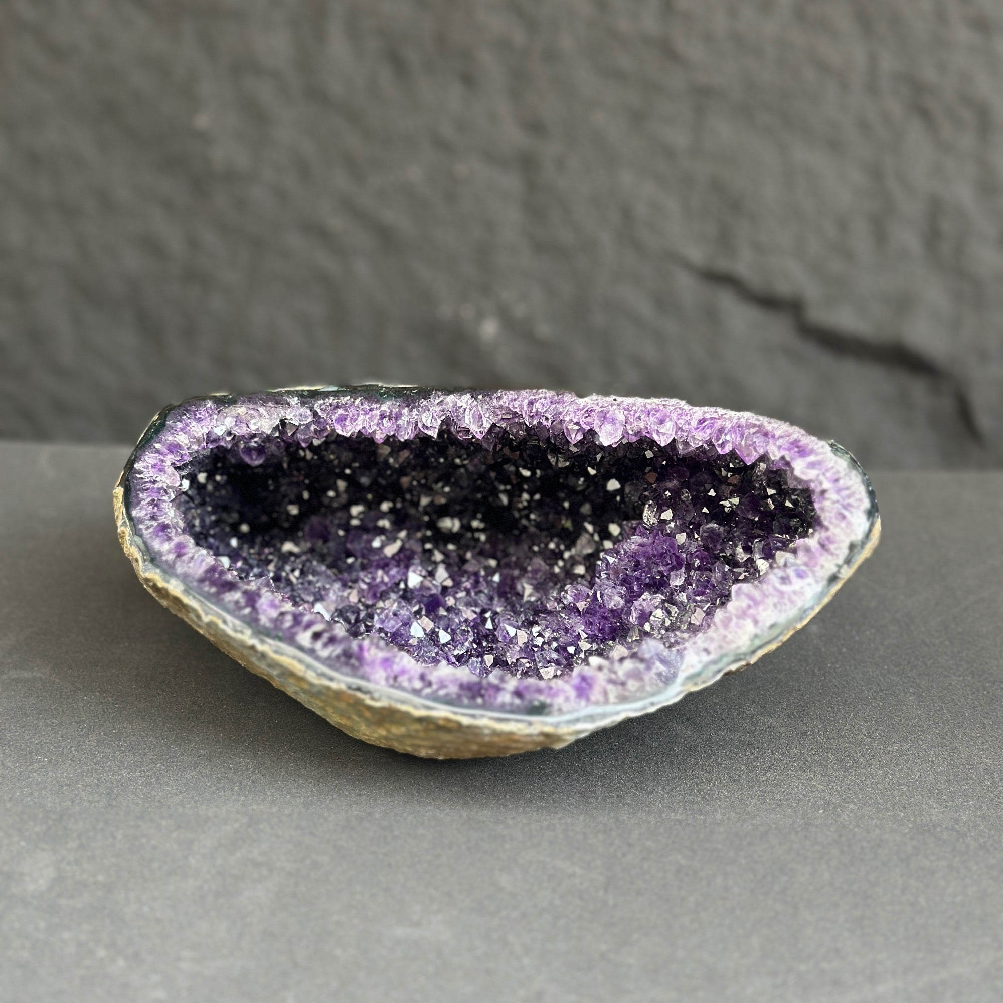 Amethyst geode on a gray surface with a dark background