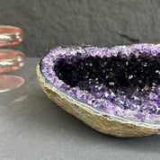 Amethyst geode on a dark surface with a gray background