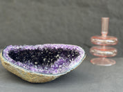 Geode crystal bowl with purple interior on a gray background