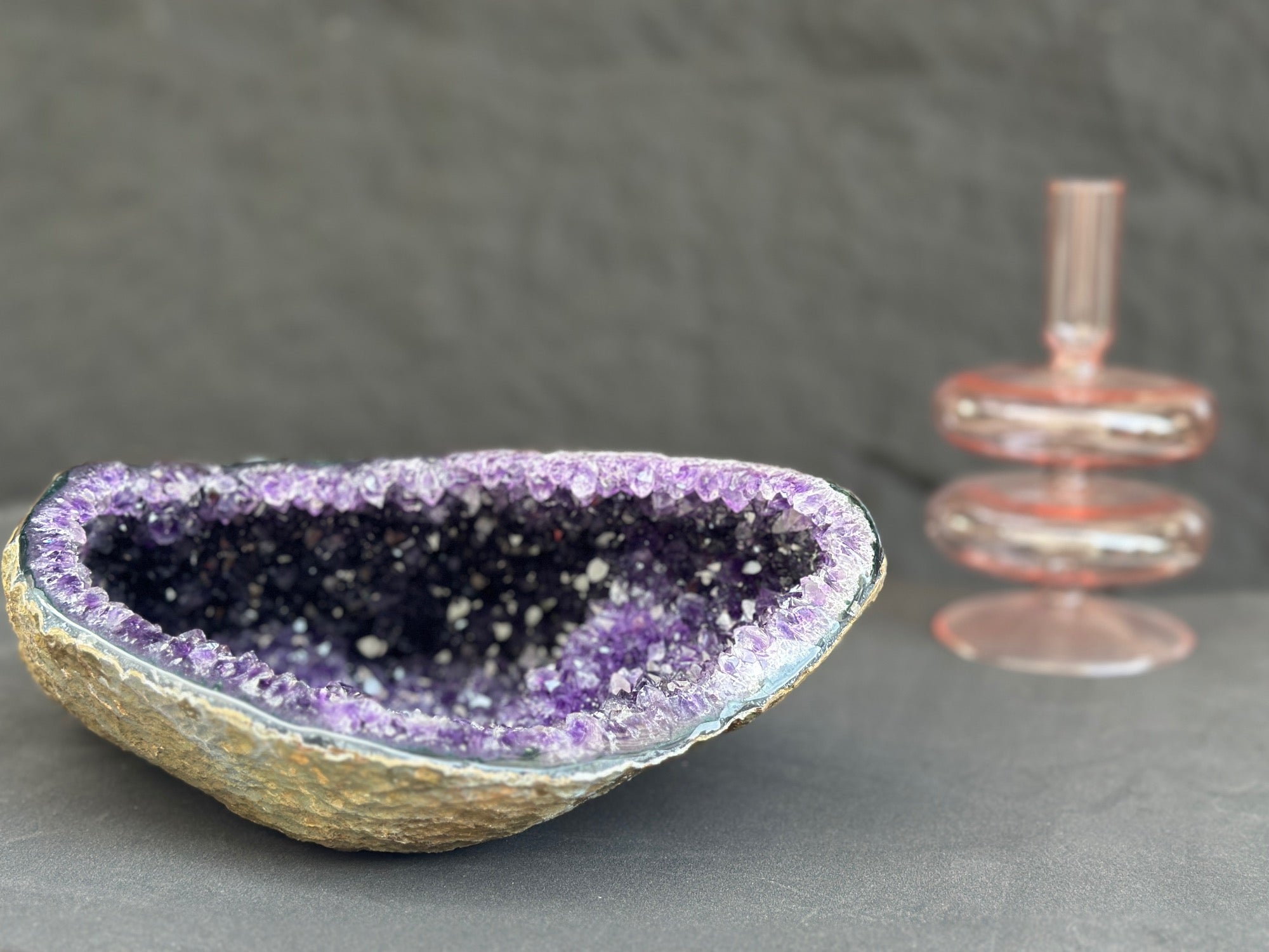 Geode crystal bowl with purple interior on a gray background