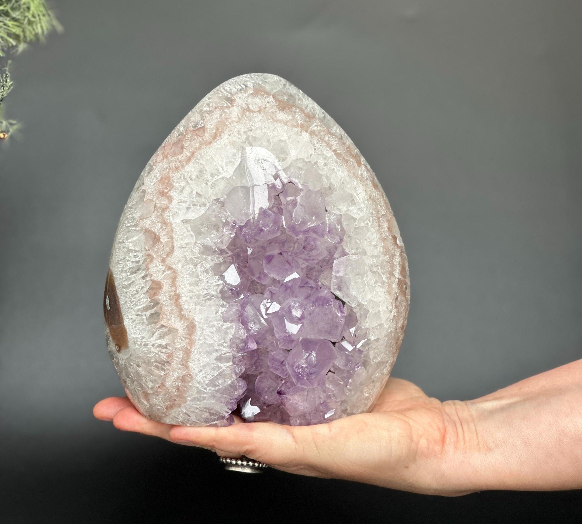 Hand holding a 7-inch Uruguayan amethyst and agate geode cave with vibrant purple crystals.