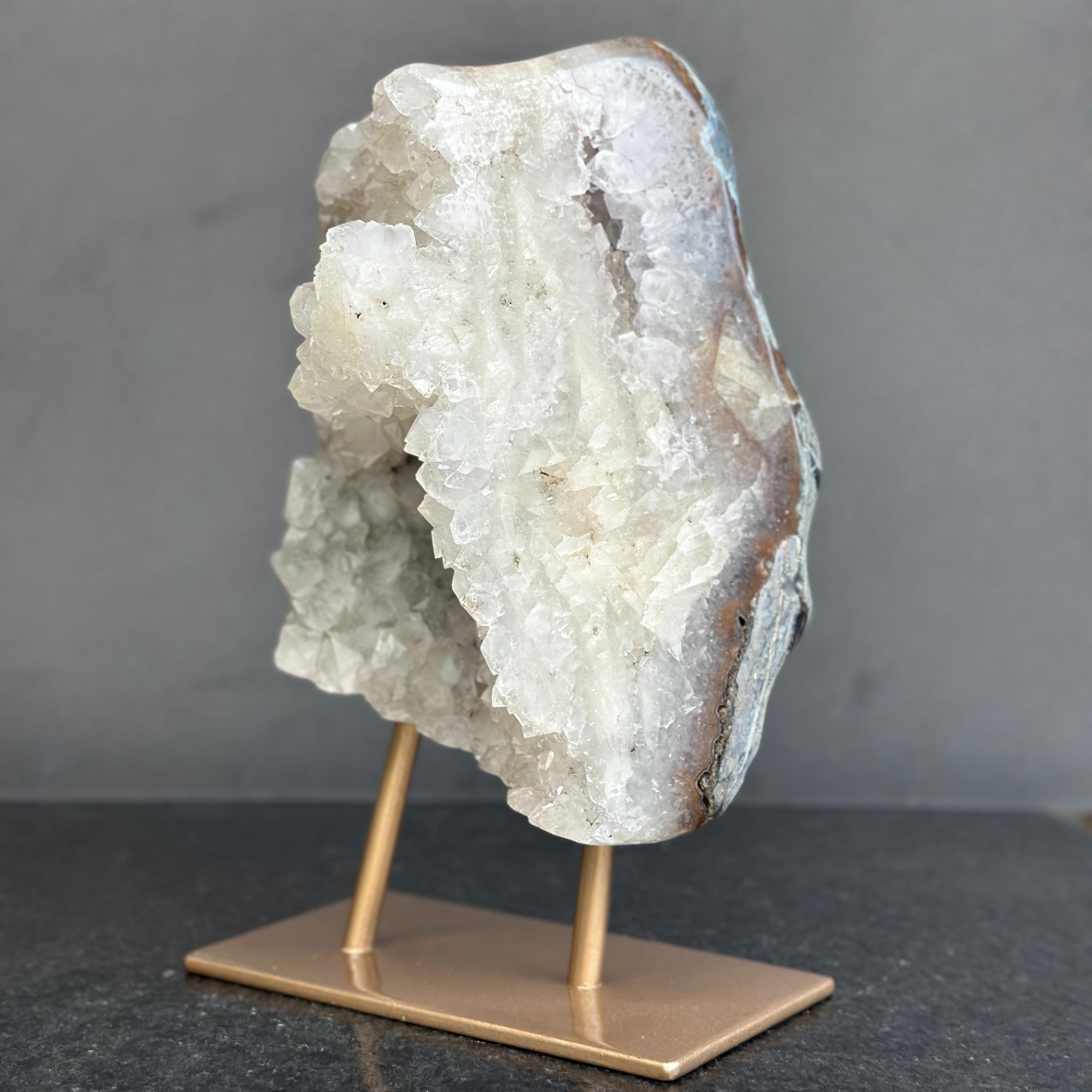 Geode crystal on a bronze stand against a gray background