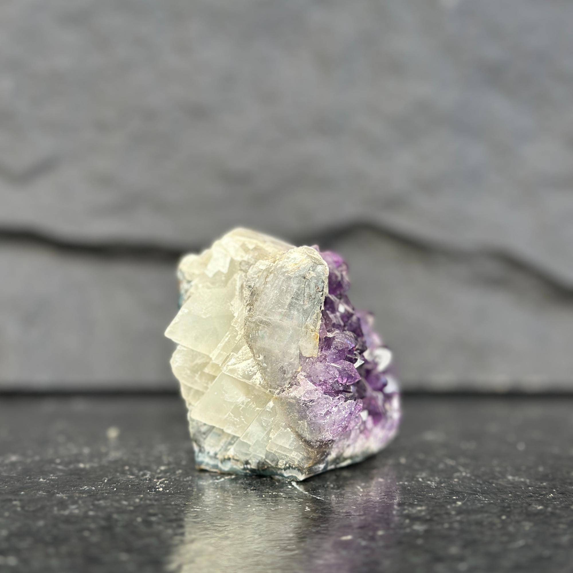 Mineral specimen with purple and white crystals on a dark surface