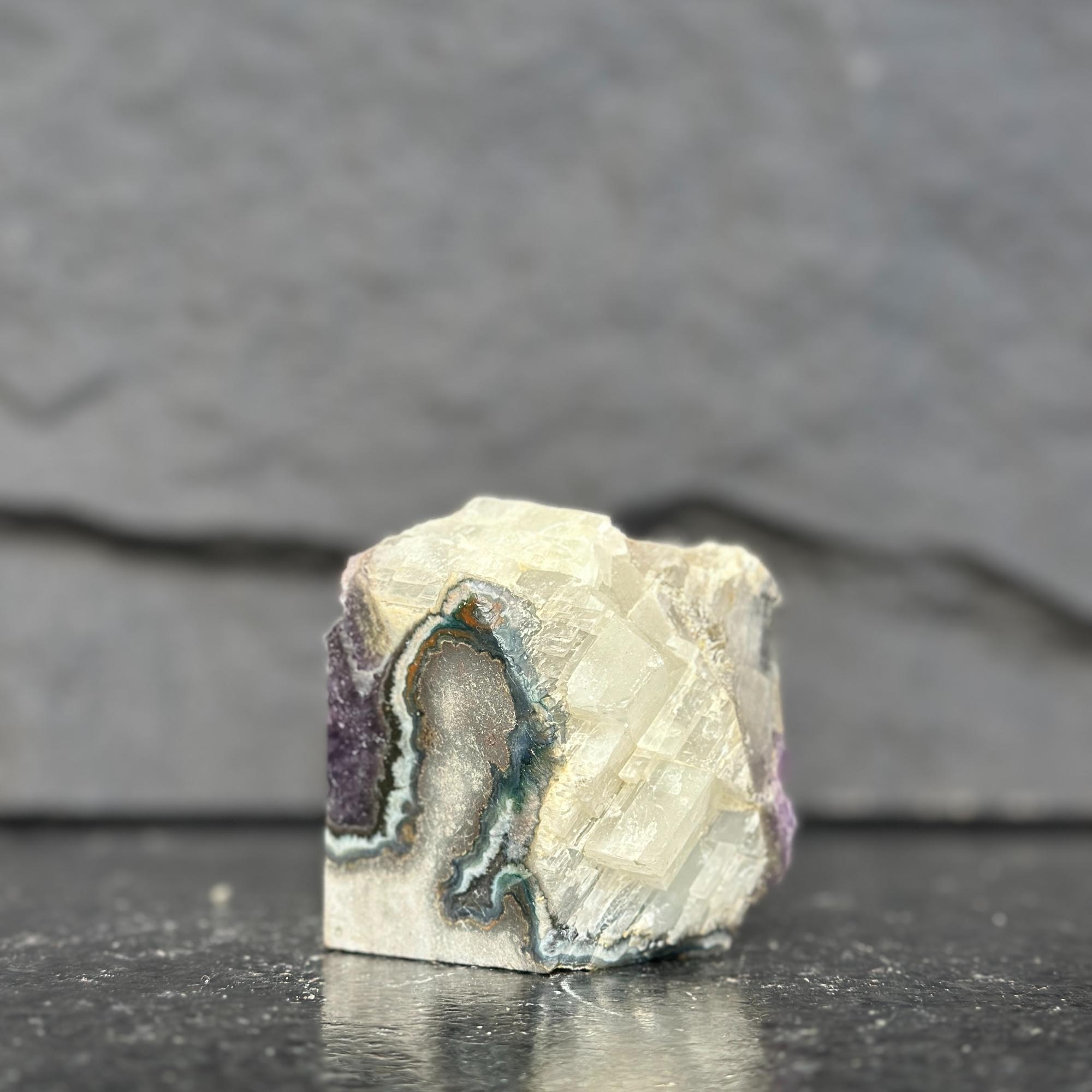 Geode crystal on a dark surface with a gray background