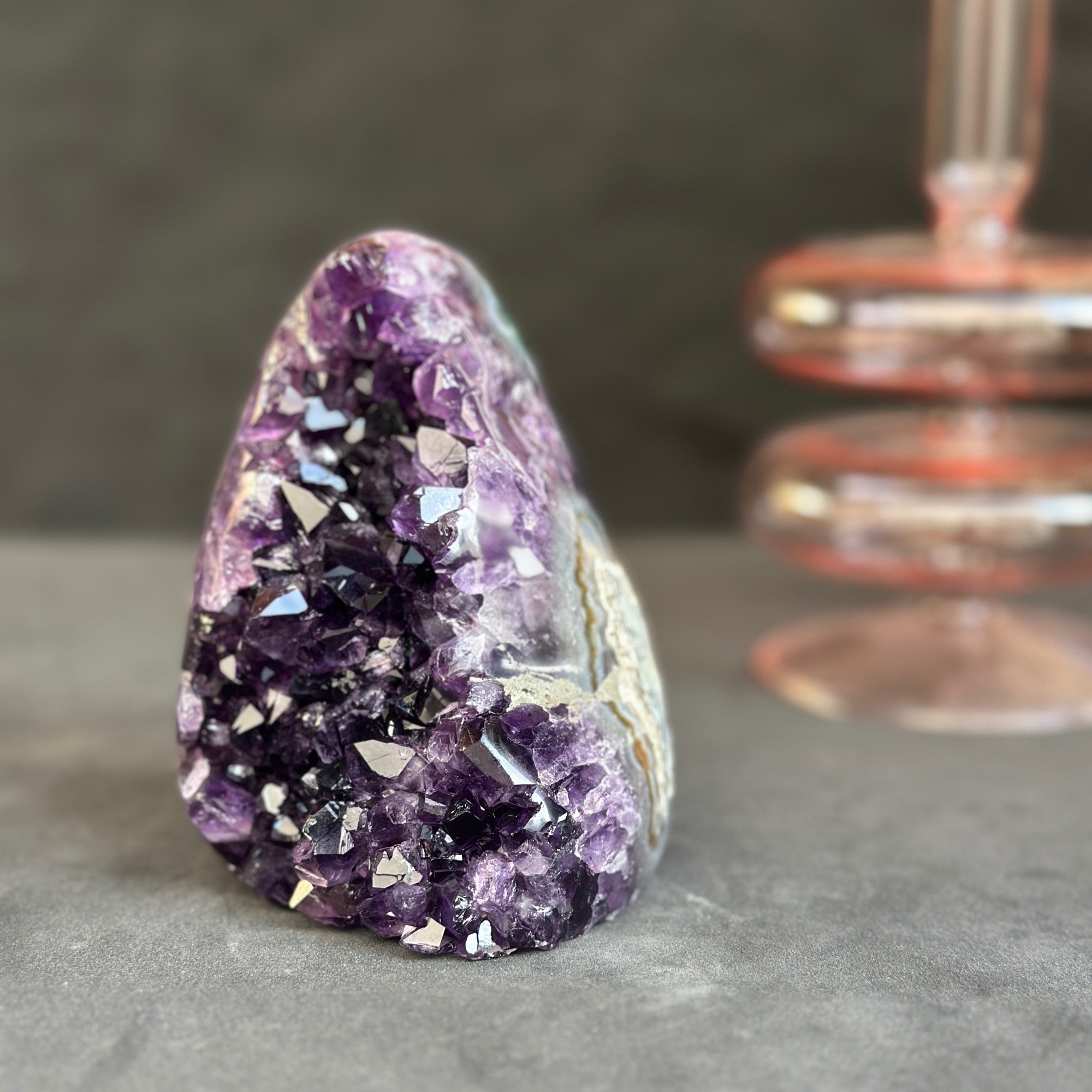Amethyst crystal on a dark surface with a blurred background