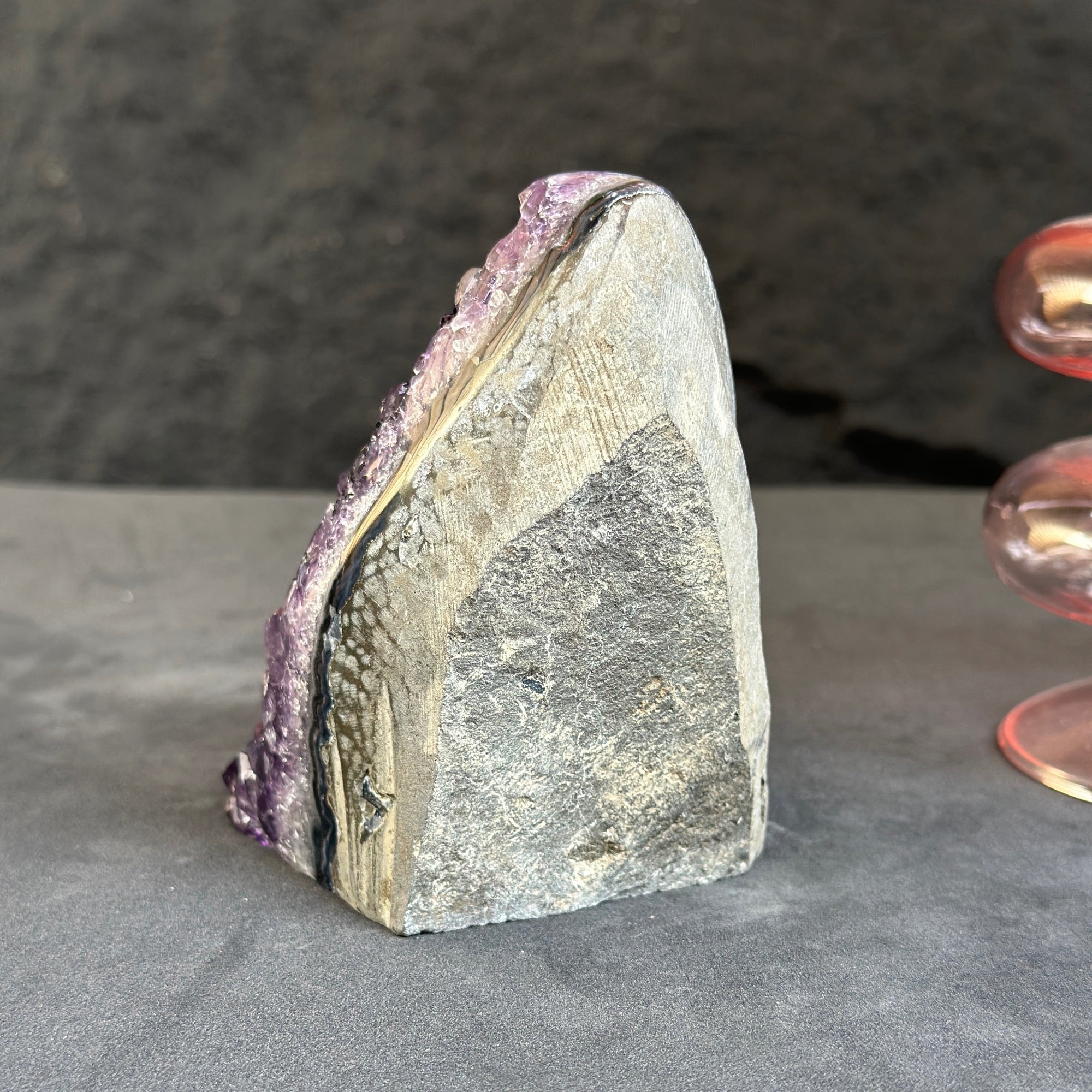 Mineral specimen with purple crystal on a gray surface