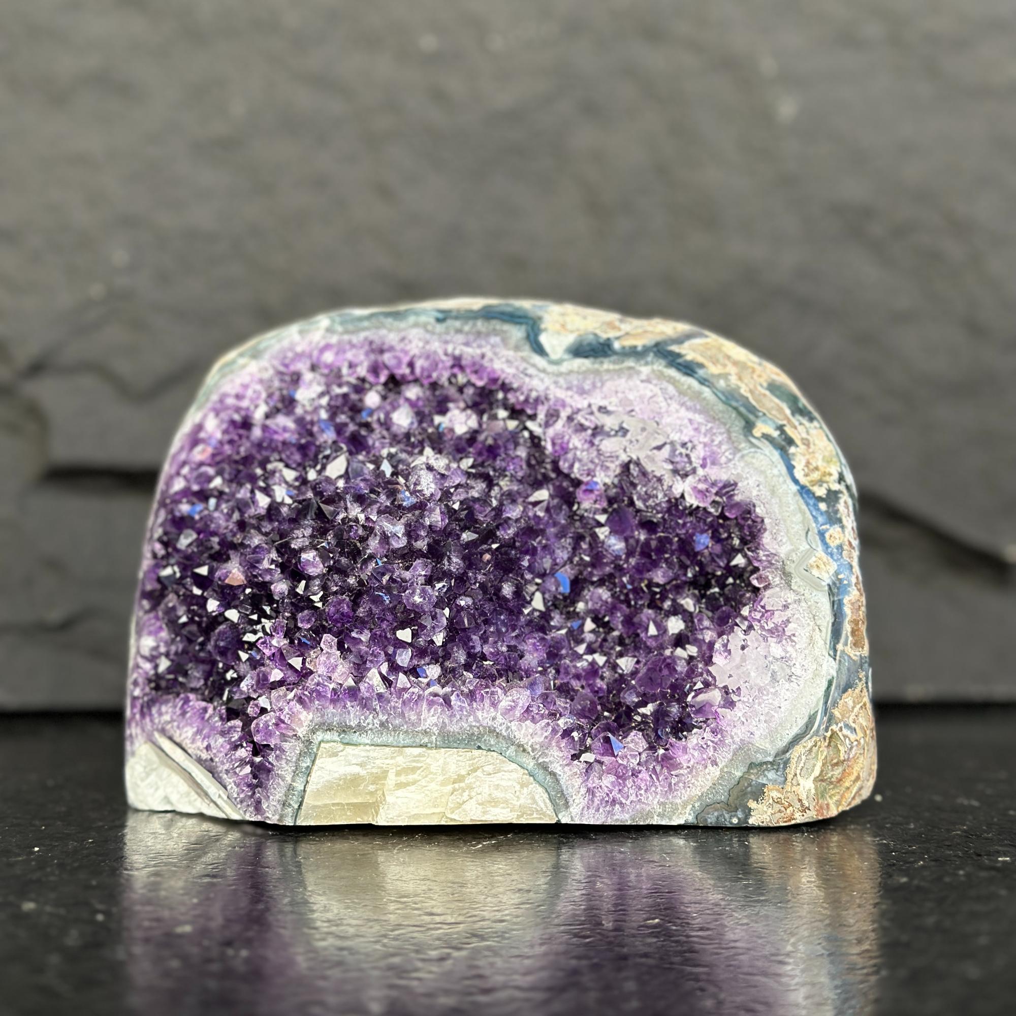 Amethyst geode on a dark surface with a gray background